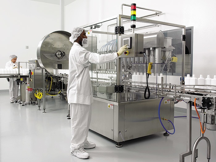 Standing in front of the eight-head piston filler, a PharmaFab employee monitors production on the company's new liquid pharmac