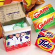 Film-laminated paperboard cartons for two Procter & Gamble dry detergent brands offer examples of the shelf 'pop' that store ma