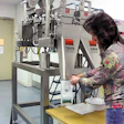 Packaging supervisor Dee Chiodo holds a bag under a funnel for seed filling. By depressing a foot pedal, she releases weighed se