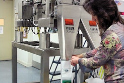 Packaging supervisor Dee Chiodo holds a bag under a funnel for seed filling. By depressing a foot pedal, she releases weighed se