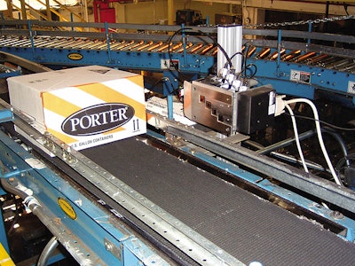 Guide rails hold cases of quart paint cans in alignment as they approach JETPACK thermal inkjet printer from PRISM. The printer