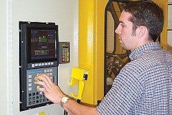 Grad student Kirk Valko dials in a new setting on the extrusion blow molding system that occupies the machinery lab at the MSU S