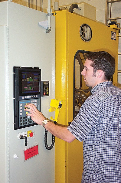 Grad student Kirk Valko dials in a new setting on the extrusion blow molding system that occupies the machinery lab at the MSU S