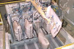 A robotic bag loader moves a new valve bag into one of the four filling stations on the filler, which has been upgraded with el