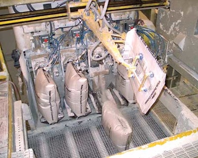 A robotic bag loader moves a new valve bag into one of the four filling stations on the filler, which has been upgraded with el
