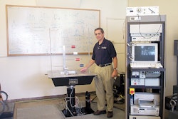 Inside the packaging lab at SJSU, packaging program director Herbert Schueneman poses next to a vibration tester.