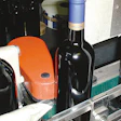 As wine bottles emerge from the heat tunnel that shrinks the capsule around the bottle neck, a vertical conveyor belt rotates th