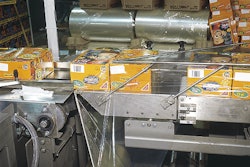 Unprinted PVC film unwinds upward to a film former just above a conveyor that moves two cartons at a time into the film in this