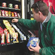 A vending machine operator stocks dog candy and breath mints in a machine at a Maine highway rest stop.