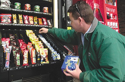 A vending machine operator stocks dog candy and breath mints in a machine at a Maine highway rest stop.