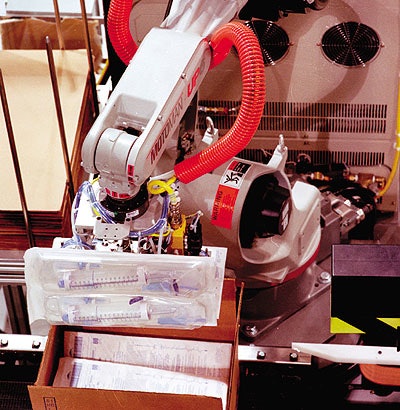 Baxter's robot picks up four blister packs at a time using a hinged gripper for placement into the cases.