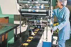 In the foreground (below), a continuous band conveyor feeds cookies by diverters into the infeeds of two parallel wrappers. An o