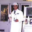 Plant manager Doros Cleanthous holds filled bottles of milk, one of which is shown close-up.