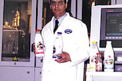 Plant manager Doros Cleanthous holds filled bottles of milk, one of which is shown close-up.