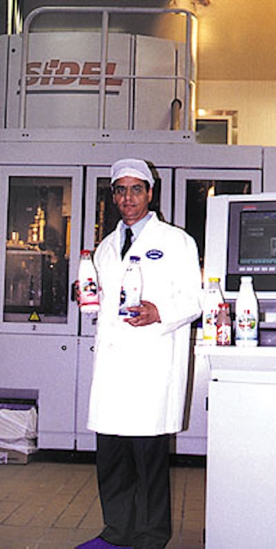 Plant manager Doros Cleanthous holds filled bottles of milk, one of which is shown close-up.