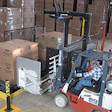 After delivering a load of boxed coolers onto the left side of the shuttle table, a clamp truck driver backs away and pulls a la