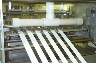 Lint is removed from the six-across pad material as it passes beneath a horizontal vacuum tube just before it is cut, folded and