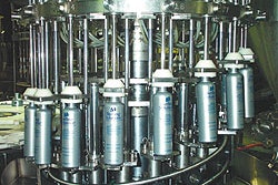 Backside view shows the cam-operated platforms under each bottle that raise and lower during the filling cycle to minimize splas