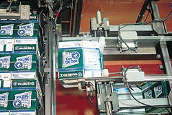 The system shown here includes a robotic positioner that picks a bundle of 12-count corrugated shippers, orients the bundle, cut