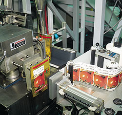 Colorful front labels are applied to pouches by a tamp labeler (top). On the can-filling side, cans are positively captured on t