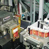 Colorful front labels are applied to pouches by a tamp labeler (top). On the can-filling side, cans are positively captured on t