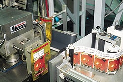 Colorful front labels are applied to pouches by a tamp labeler (top). On the can-filling side, cans are positively captured on t