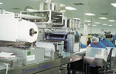Workers remove packs of surgical gloves from the Tiromat Powerpak (top), a machine equipped with the patented Infrasync drive.