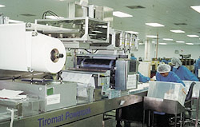Workers remove packs of surgical gloves from the Tiromat Powerpak (top), a machine equipped with the patented Infrasync drive.