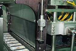 Robotic pick-and-place tool (top) loads eight trays at a time into carrier plates that deliver the trays to the evacuation/backf