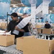 An eToys operator inspects a boxed order to determine how many air cushions will be necessary to prevent excessive product movem