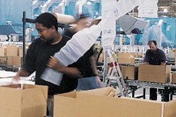 An eToys operator inspects a boxed order to determine how many air cushions will be necessary to prevent excessive product movem