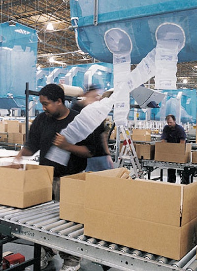 An eToys operator inspects a boxed order to determine how many air cushions will be necessary to prevent excessive product movem