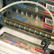 The labeler uses two parallel conveyors (below). In this photo, an open, toothbrush-filled case enters the machine from the conv