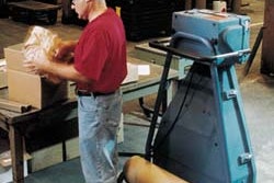 A customer service employee at Mathews uses the PadPak Jr. to prepare spare parts for shipment.