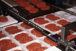 Formed beef patties are automatically dropped into formed trays by a retractable conveyor system