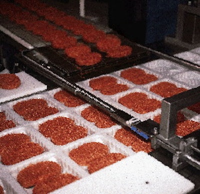 Formed beef patties are automatically dropped into formed trays by a retractable conveyor system