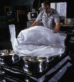 An operator at AAP St. Marys (above) places an aluminum wheel in the molded recess of a high-density polyethylene tray. Each lay
