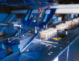 The output from all ten robots is handled by a single flow wrapper that wraps trays at 90/min (right). Operators can monitor the