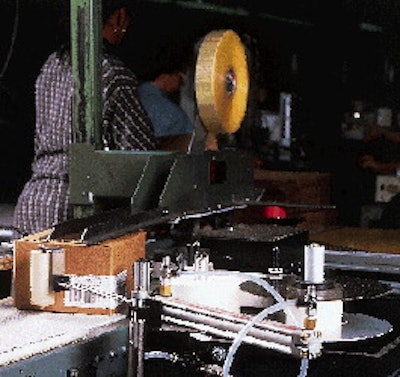 The white roller on a swinging extension arm smoothes down the front of the label even as the case moves forward (above). Cases