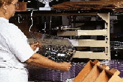 At Lucent1s Columbus, OH, plant, a worker loads a printed circuit board into a clamshell at a work station