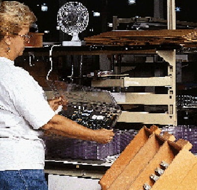 At Lucent1s Columbus, OH, plant, a worker loads a printed circuit board into a clamshell at a work station