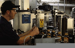 A line operator looks at beer bottles as they pass the second inspector on the line. This unit checks for label placement and ma