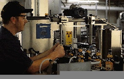 A line operator looks at beer bottles as they pass the second inspector on the line. This unit checks for label placement and ma