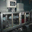 A group of mechanical fingers (shown at bottom left in the photo at left) remove six blow-molded 1-gal HDPE jugs and place them