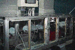 A group of mechanical fingers (shown at bottom left in the photo at left) remove six blow-molded 1-gal HDPE jugs and place them