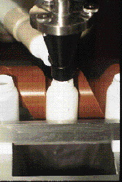 At the pre-tare station (above), empty bottles are individually weighed, then conveyed to the dosing station (left). A dust shr