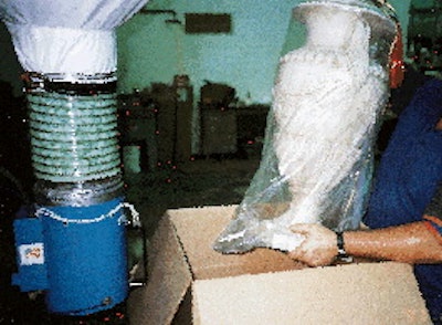 A prewrapped lamp base is lowered into the lower base layer of Enviromold within a carton