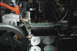 Vacuum arms pick two separate pieces of corrugated from a magazine and position them on opposite sides of the center can to serv