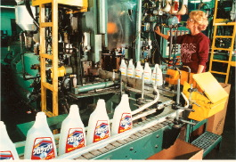Machine operator Martha Johnson evaluates finished bottles slated for overseas distribution as they move along the line at the O