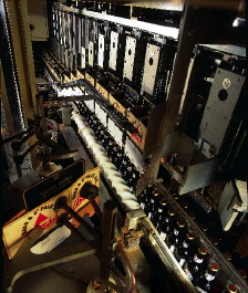 Pre-glued basket carriers with unsealed bottoms are placed in moving flights that guide the carriers over bottle groupings, afte